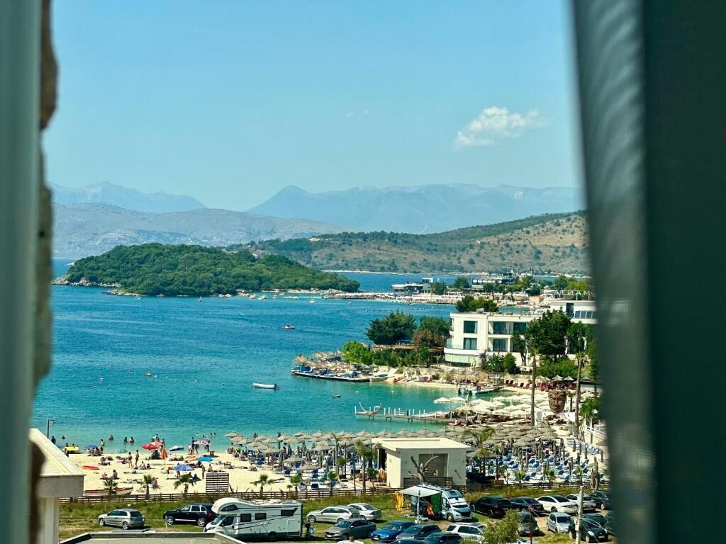 Une vue sur la côte, avec une plage, des voitures garées et des bâtiments.