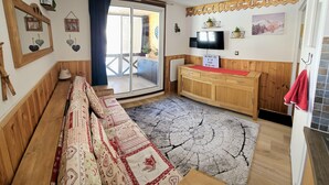 Quarto aconchegante com sofá, televisão, armário de madeira e placa de boas-vindas.