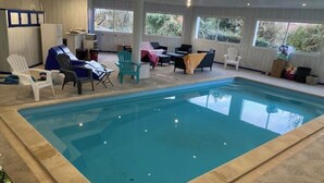An indoor swimming pool with a tiled border, surrounded by lounge chairs and tables. - LA TOUR DE SAINT XANDRE LA ROCHELLE (Saint-Xandre)