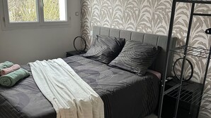 A bedroom with a bed, a bedside table, a lamp, and a window. - LA TOUR DE SAINT XANDRE LA ROCHELLE (Saint-Xandre)
