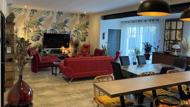 A modern living room with a red sofa, a dining table with chairs, and a television. - LA TOUR DE SAINT XANDRE LA ROCHELLE (Saint-Xandre)
