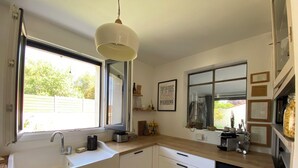A modern kitchen with white cabinets, a built-in dishwasher, a large window, and a pendant light. - House with swimming pool and large garden near the sea (Montbazin)