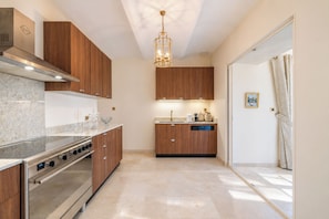 A modern kitchen with wooden cabinets, a stainless steel oven, and a pendant light. - Mas de Louise (LUSSAS)