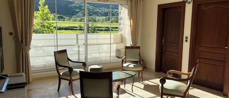 A room with a large window, wooden furniture, and a door.