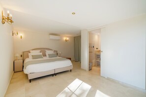 A bedroom with a bed, bedside tables, a wardrobe, and a bathroom visible through an open door. - Mas de Louise (LUSSAS)