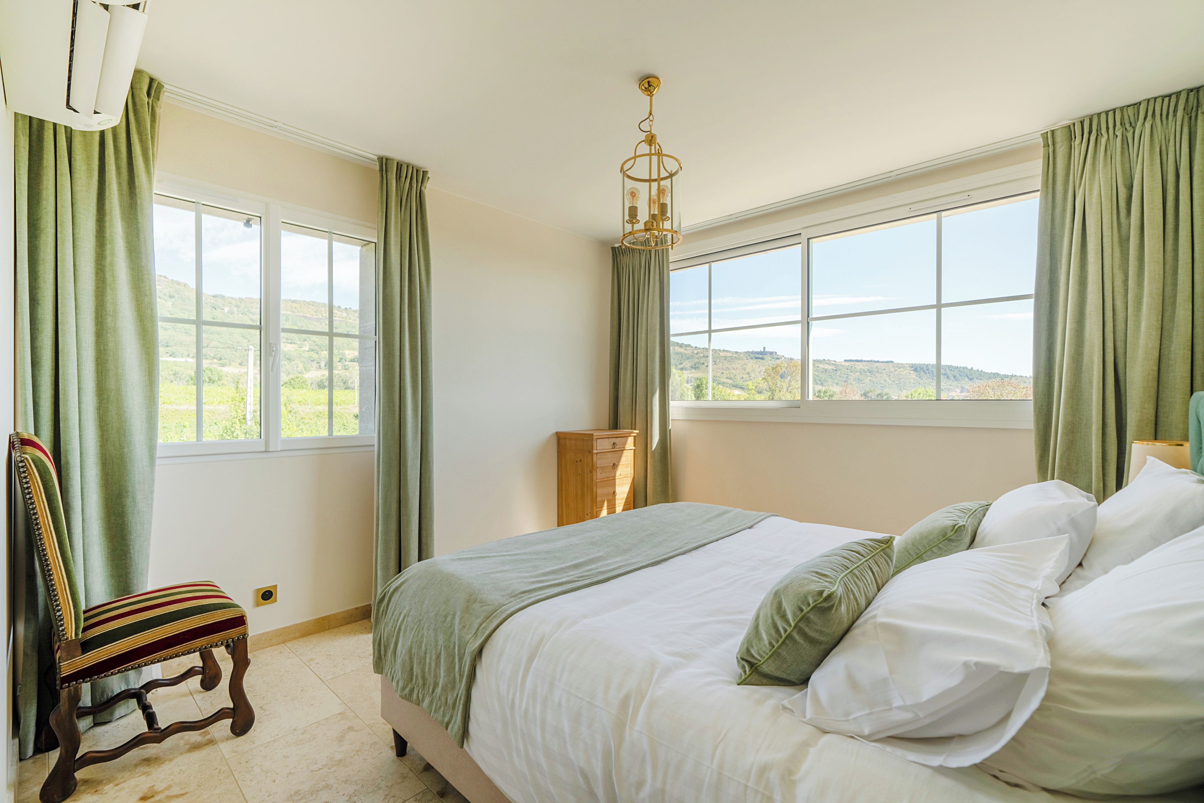 Une chambre à coucher comprenant un lit, une chaise, une commode et une fenêtre donnant sur le paysage.