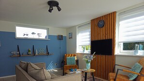 En stue med sofa, lænestole, sofabord, fjernsyn og en trævægsbeklædning.