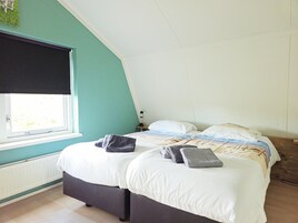 Un dormitorio con una cama, una ventana, un radiador y una mesita de noche con una lámpara.