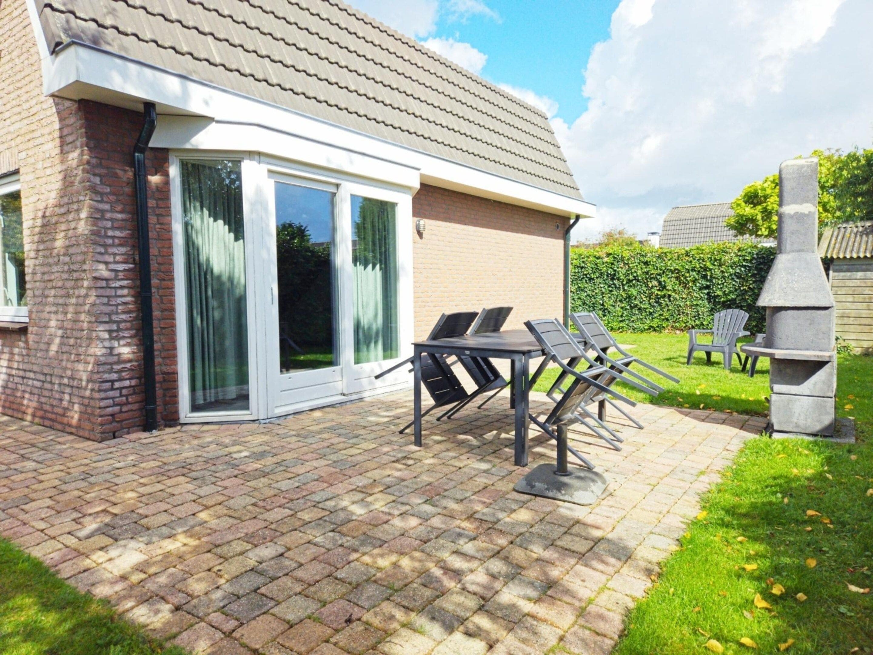 A patio with a brick floor, a table with chairs, and a barbecue grill.