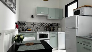 Cozinha moderna com eletrodomésticos brancos, armários verde-claros e um backsplash estampado.