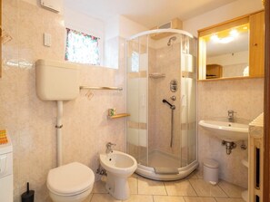Ein Badezimmer mit Toilette, Bidet, Duschkabine, Waschbecken und Spiegel.