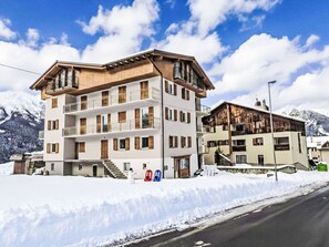 Ein mehrstöckiges Hotel mit Balkonen und einem verschneiten Berggrund.
