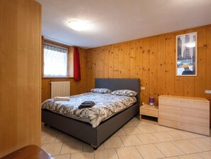 Ein Schlafzimmer mit Bett, Schminktisch, Fenster mit Vorhängen und einem Bild an der Wand.