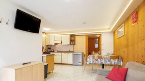 Een compacte leefruimte met een kitchenette, een eethoek en een bank.
