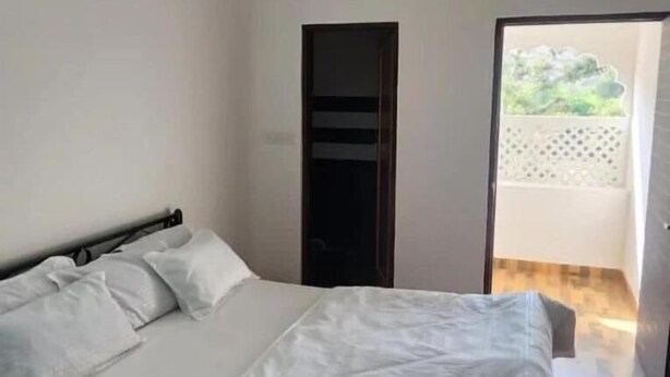 A bedroom with a bed, a door, and a view of a balcony. - Shree Siddhivinayak Hotel  (Achrol)