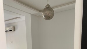 Un comedor moderno con una mesa de mármol, sillas negras y una lámpara colgante.