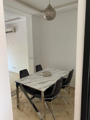 A modern dining area with a marble table, black chairs, and a hanging light fixture. - Balqis' haven of peace (Marrakech)
