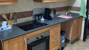 Una cocina con gabinetes de madera, un lavamanos de acero inoxidable, una estufa y una cafetera.