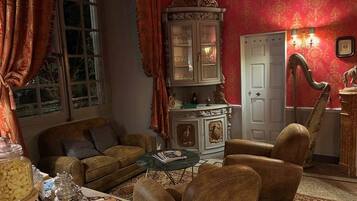 Un salon traditionnel avec un canapé, des fauteuils, un buffet et une table.