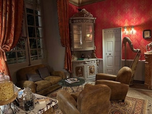 Un salon traditionnel avec un canapé, des fauteuils, un buffet et une table.