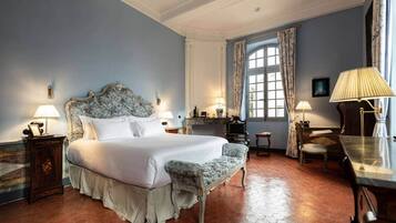 Habitación de hotel con una cama grande, un escritorio, una silla y un ventanal con cortinas.