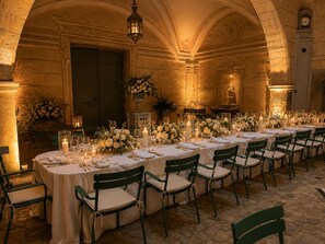 A long table set for a formal event with chairs, candles, and floral arrangements.