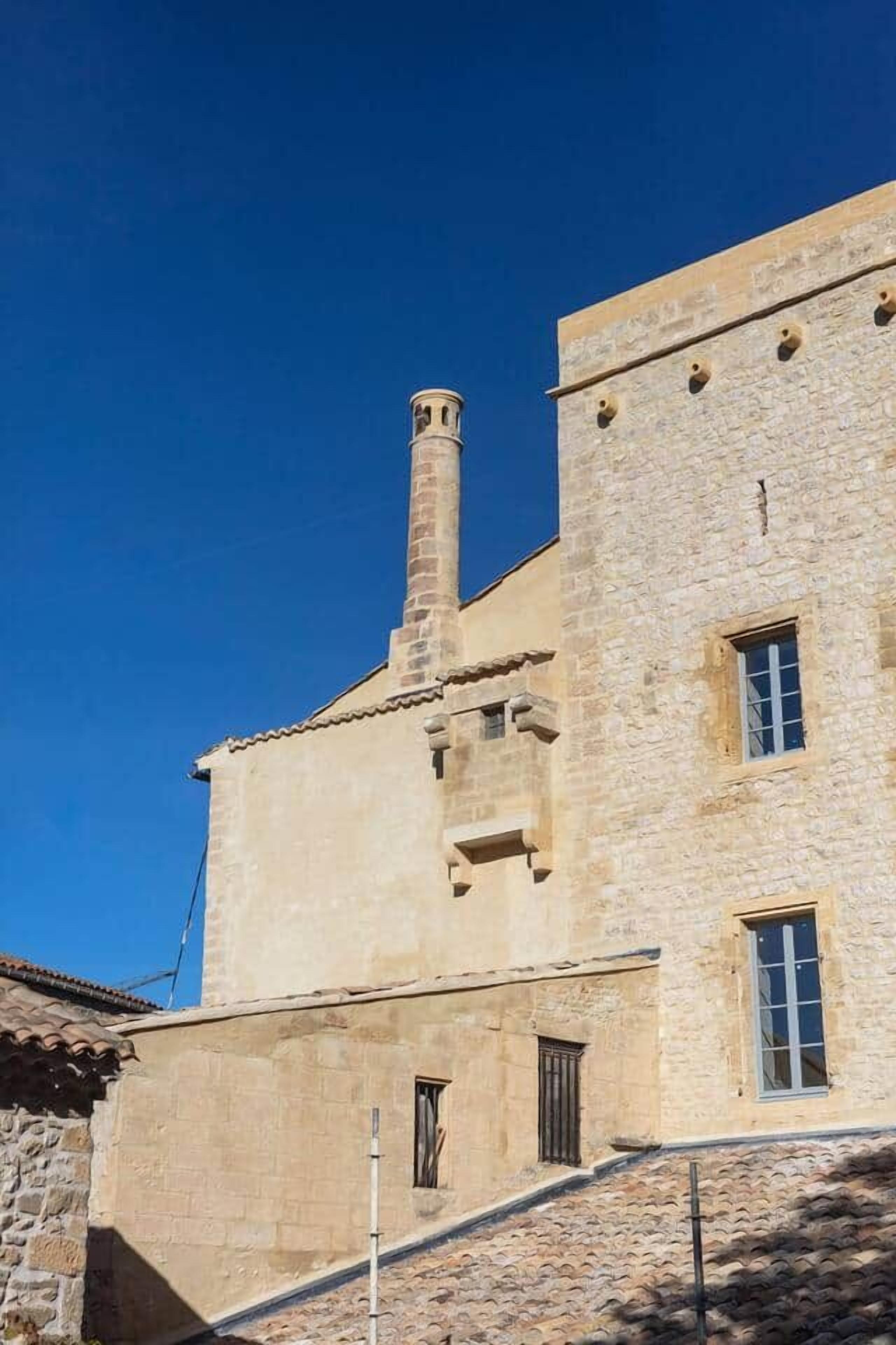 Un bâtiment en pierre doté d’une cheminée, d’une fenêtre et d’une porte.
