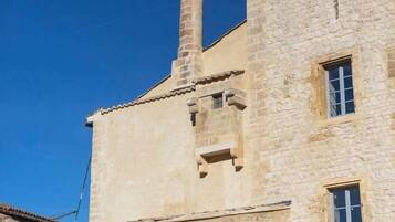 Un bâtiment en pierre doté d’une cheminée, d’une fenêtre et d’une porte.