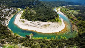 A river winding through a forested area with a sandy beach.