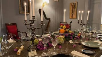 Une table à manger décorée avec de nombreuses bougies, de la verrerie et un centre de table composé de fruits.