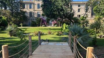 Un sentier en bois mène à un bâtiment doté d’un jardin et d’une fontaine.