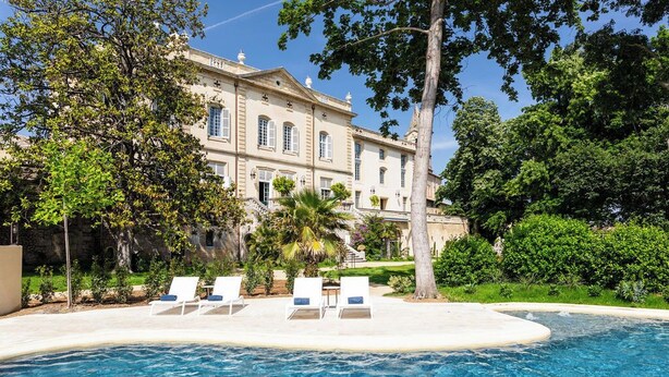 A large building with a swimming pool and lounge chairs.