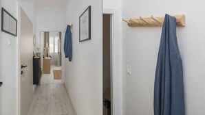 Un corridoio con pavimento in legno, un appendiabiti con un asciugamano blu e una porta che dà su un bagno.