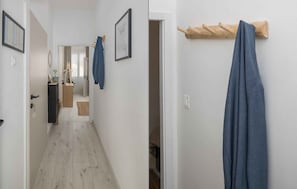 Ein Flur mit Holzboden, einem Kleiderständer mit blauem Handtuch und einer zur Toilette führenden Tür.