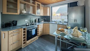 Uma cozinha moderna com armários de madeira, forno embutido e janela com vista para uma área residencial.