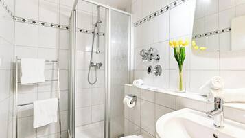 Ein modernes Badezimmer mit Glasdusche, Toilette, Waschbecken und Spiegel.