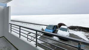 Uma varanda com vista para uma paisagem nevada e carros estacionados.
