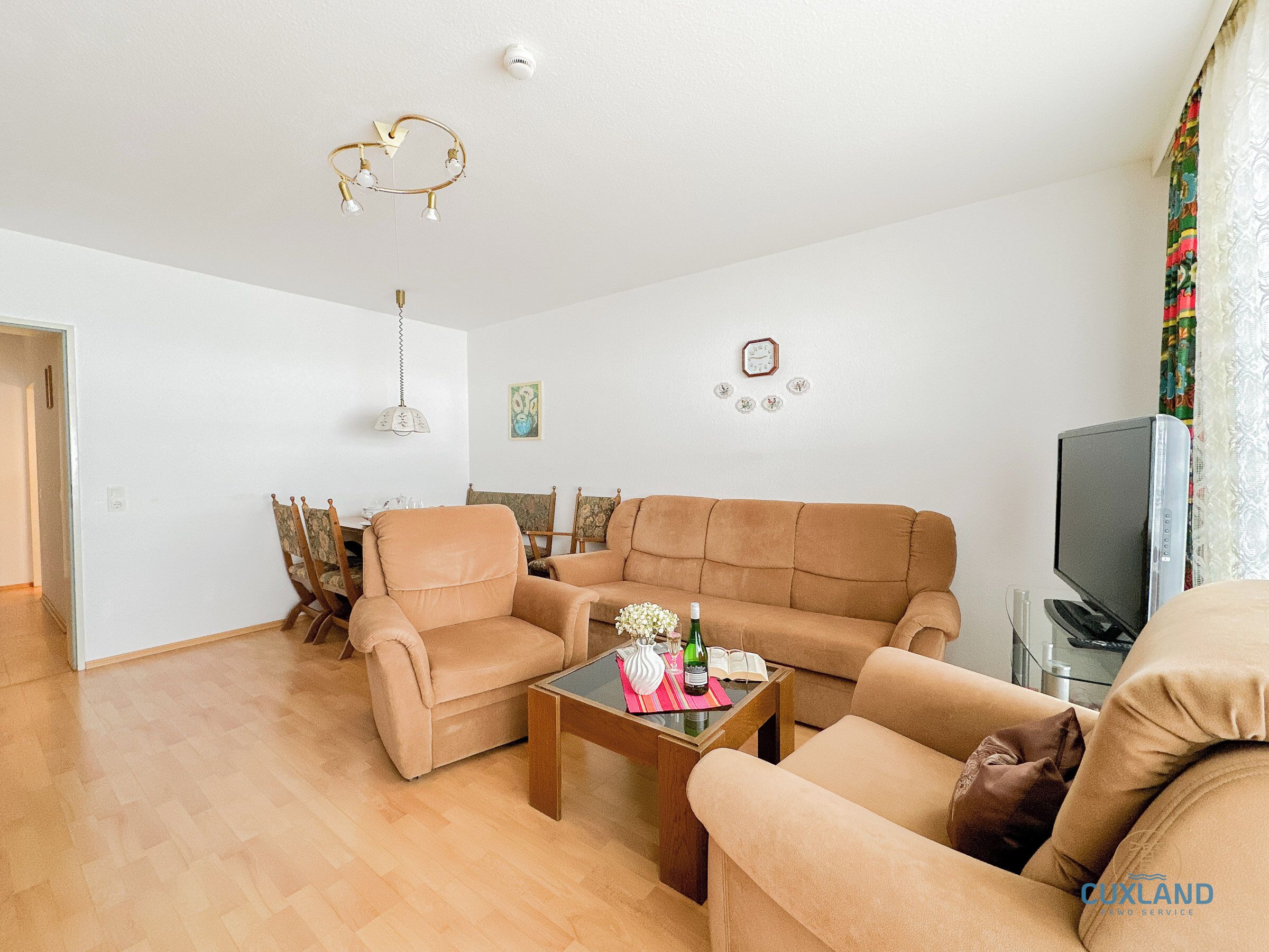 A living room with a beige sofa, a wooden coffee table, and a television.