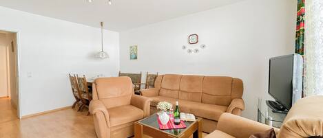 A living room with a beige sofa, a wooden coffee table, and a television.