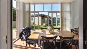 A dining area with a table, chairs, a decorative vase, and a scooter outside. - me-Elohim  (Mossel Bay)
