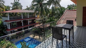 A hotel with a pool, outdoor seating, and a view of palm trees. - Palette Orient Greenz Pench by Checkin (Kurai)