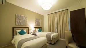 Une chambre d’hôtel avec deux lits, un bureau, une chaise et deux œuvres d’art murales.