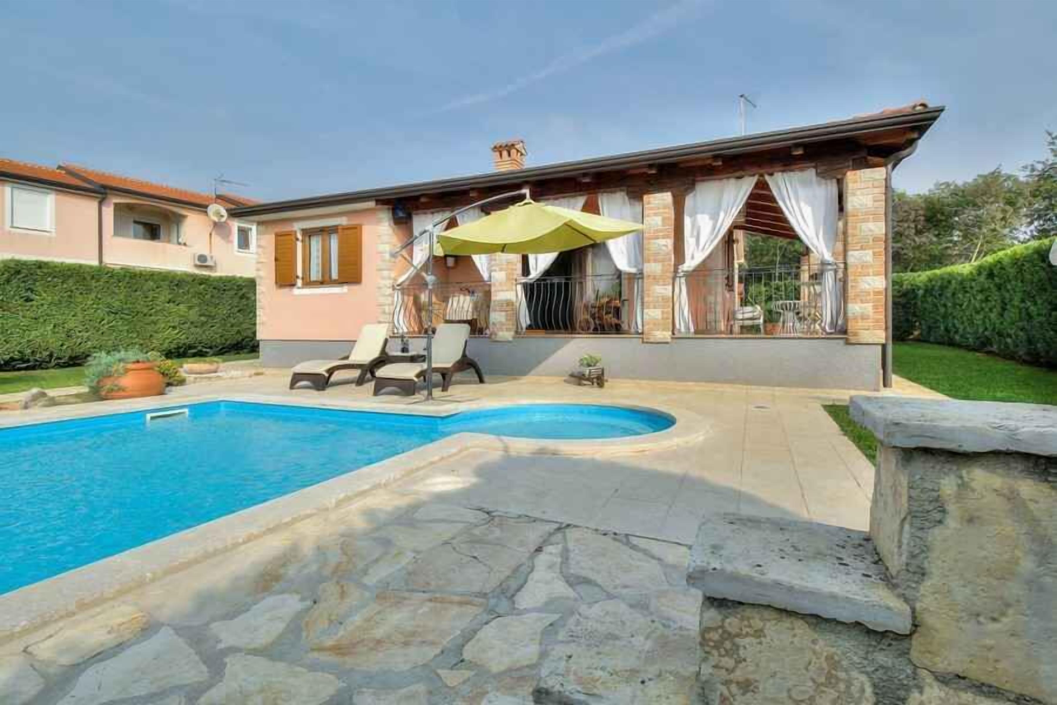 Una casa con piscina, un portico coperto con sedie e un vialetto in pietra che conduce alla piscina.