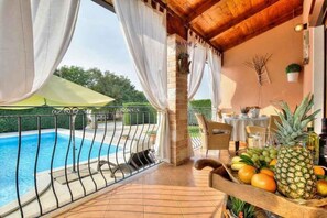 A balcony with a pool, white curtains, and a table with fruits. - Villa with private pool (Tar/Poreč)