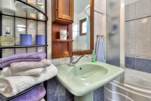 A bathroom with a green sink, a mirror, a shower area, and a shelf with towels and toiletries. - Villa with private pool (Tar/Poreč)