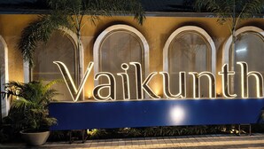 A sign with illuminated letters spelling "Vaikunth" against a textured wall with arched windows. - Vaikunth Village Resort (Abhanpur)