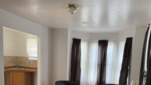 Une chambre d’hôtel équipée d’un lit, d’une table de chevet, d’une lampe et offrant une vue sur un coin cuisine.