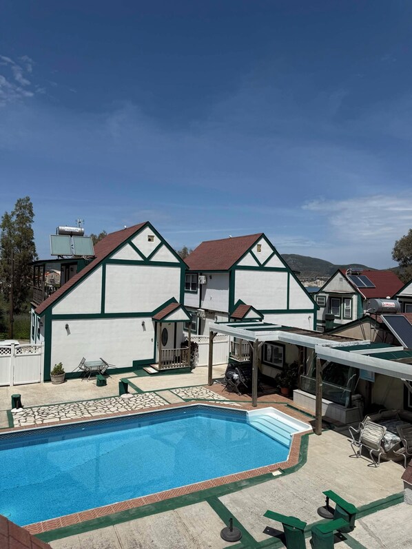 A residential property with a swimming pool, a covered patio, and a garage.