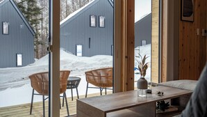 Een modern interieur met een houten vloer, een bank, een salontafel en rieten stoelen.