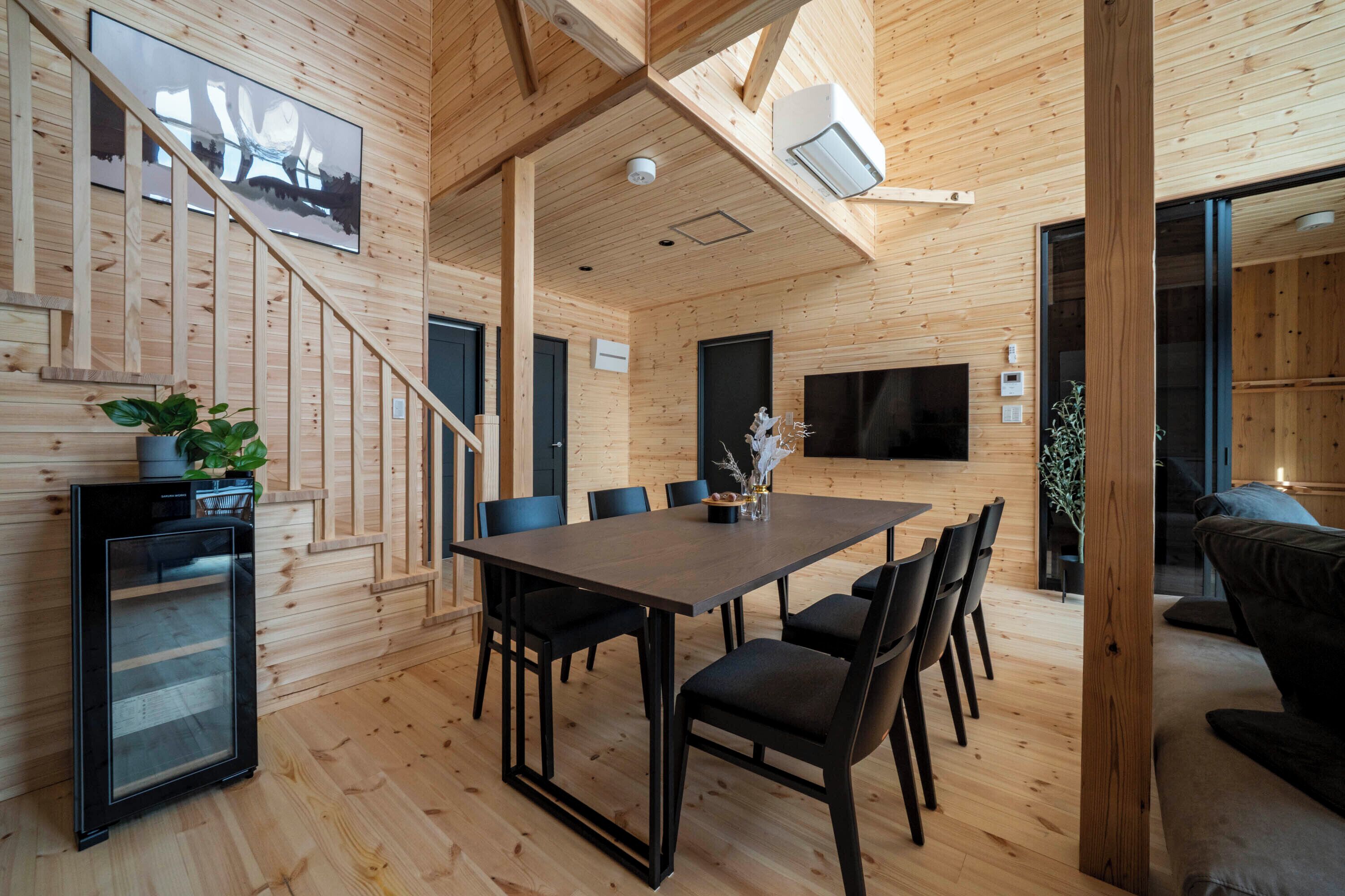 Un interior de madera con una mesa de comedor, sillas, un refrigerador y un sofá.